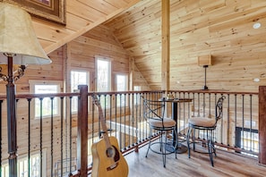 Una baita in legno con un balcone, una chitarra e un tavolo con sedie.