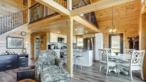 A spacious cabin interior with a dining area, kitchen, and a staircase leading to a loft. - Newfound Lake Getaway: Cabin w/ Deck, Fire Pit (Bristol)