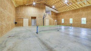 An indoor sports facility with a basketball court, wooden walls, and a high ceiling. - Spacious Barndominium Near Branson w/ Game Rooms (Omaha)