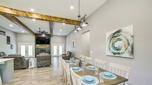 A spacious dining area with a wooden table, white chairs, and a modern ceiling fan. - Spacious Barndominium Near Branson w/ Game Rooms (Omaha)