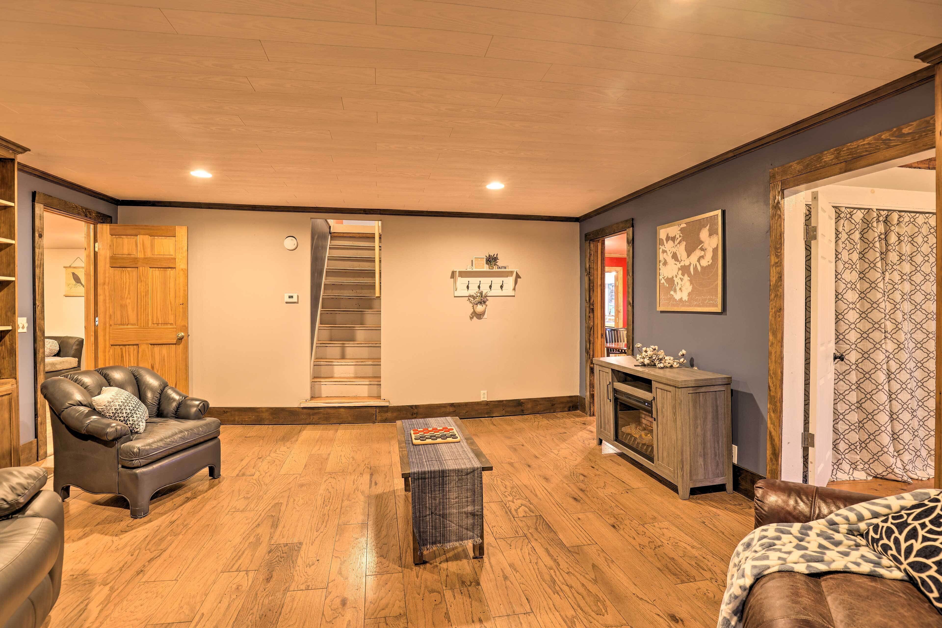 A spacious living room with hardwood flooring, a leather sofa, a coffee table, and a fireplace.