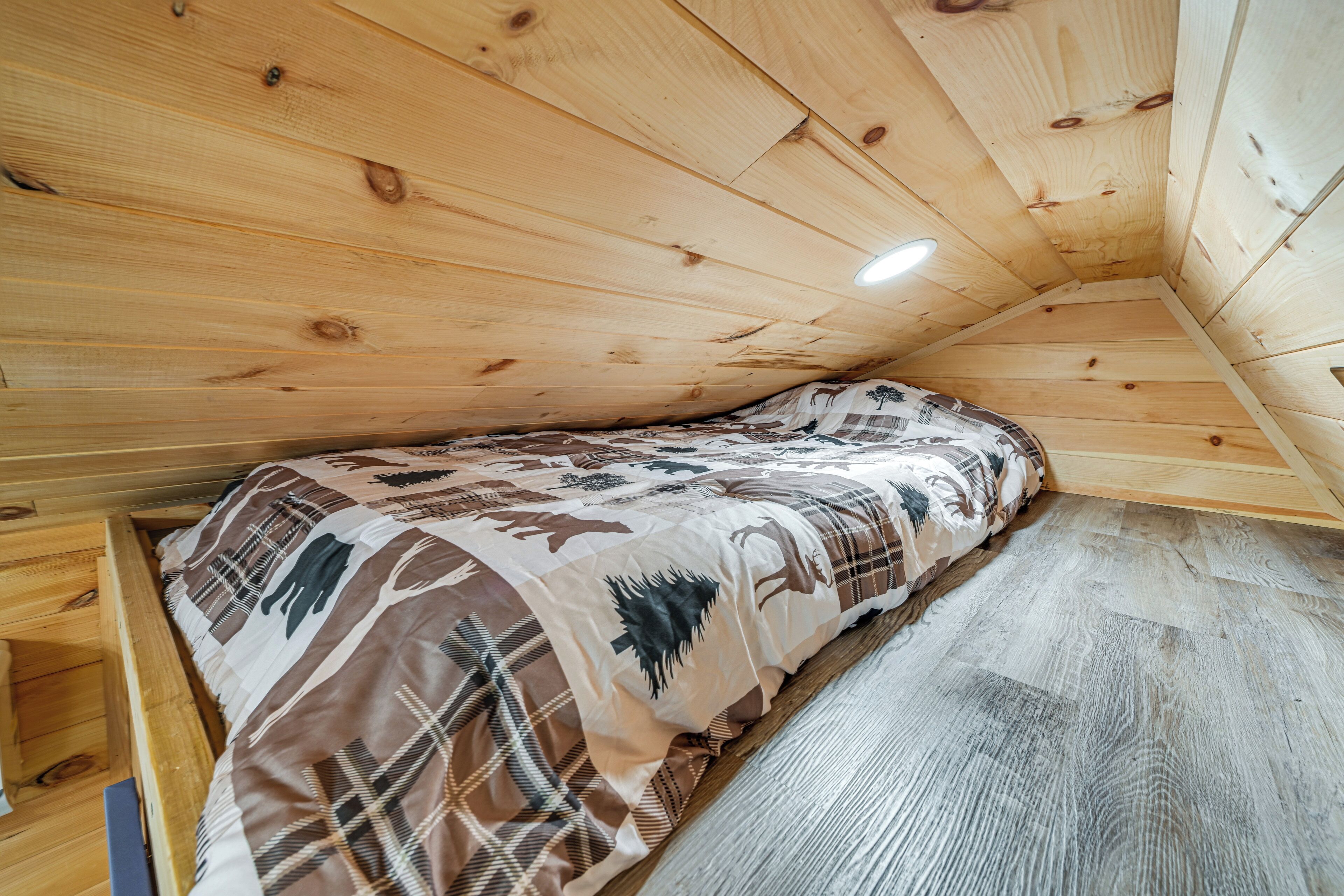 A small, cozy room with a wooden ceiling and a bed with a patterned bedspread.