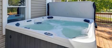 A hot tub on a wooden deck with a house in the background.