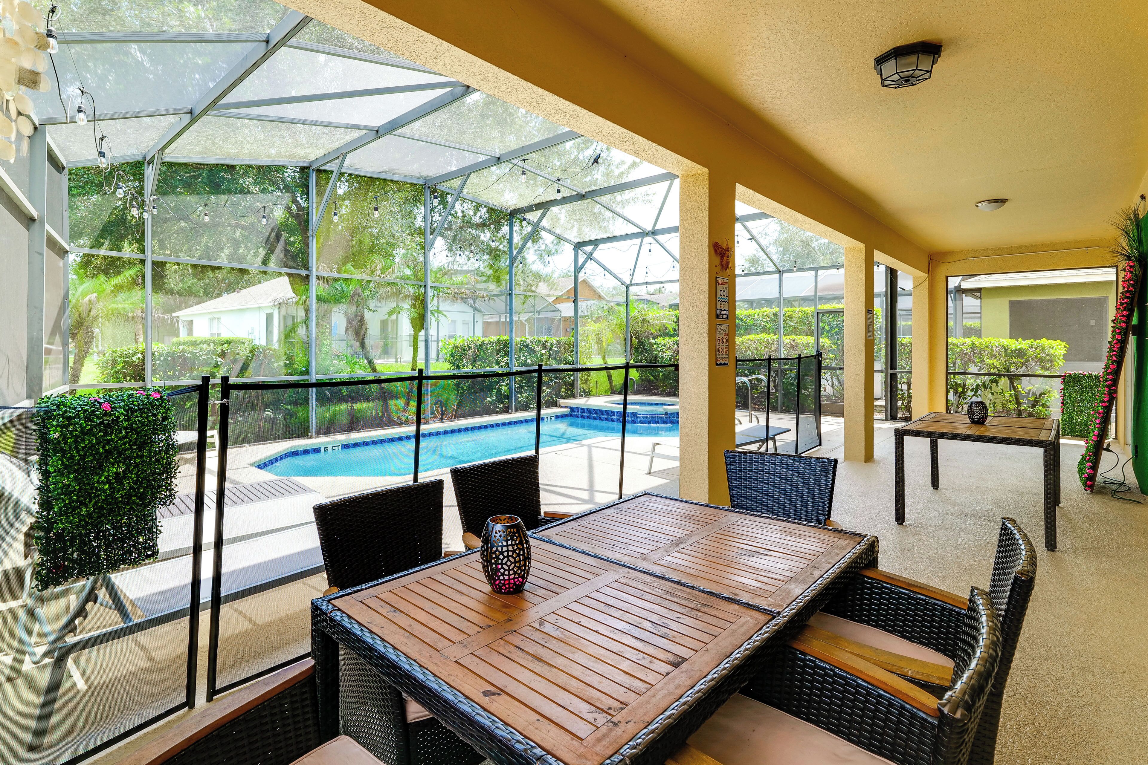 An outdoor patio area with a pool, wicker furniture, and a glass enclosure.