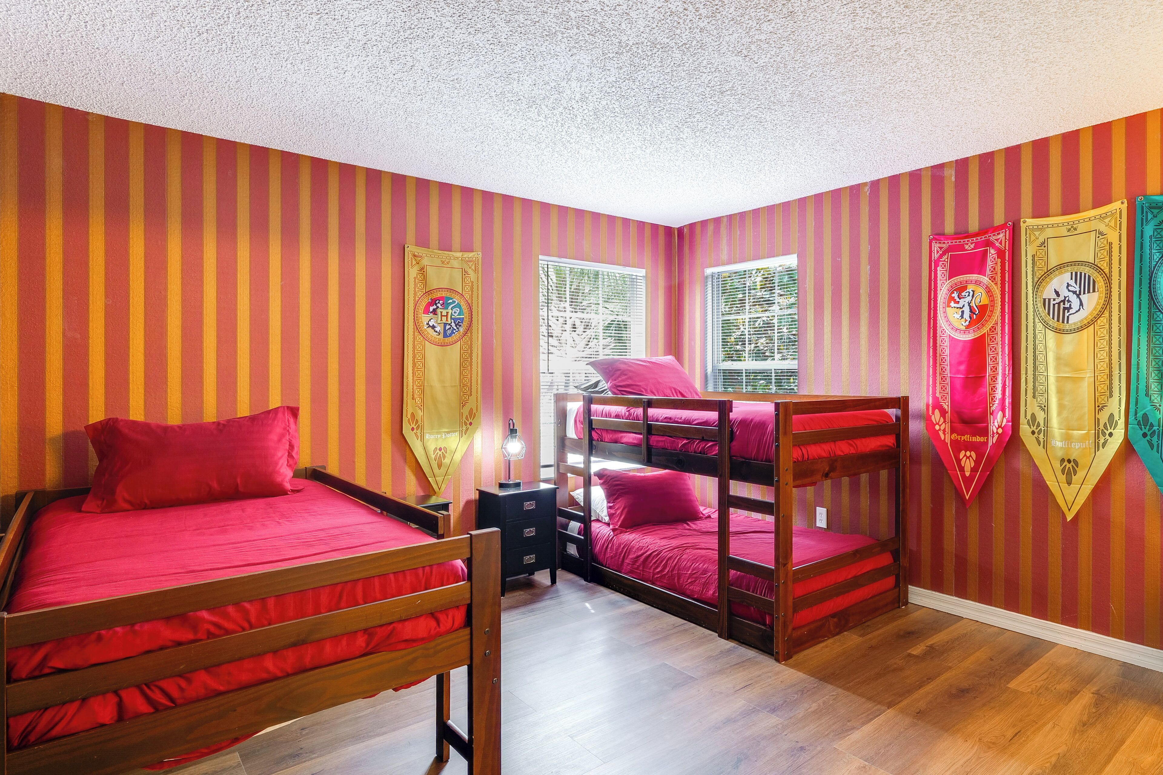 A room with a bunk bed, a single bed, and a nightstand.