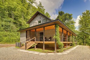 A two-story wooden cabin with a covered porch and a staircase leading to the entrance.