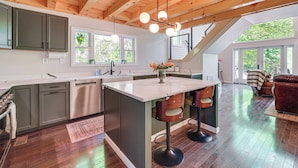 A modern kitchen with a central island, bar stools, and a dining area with a sofa.