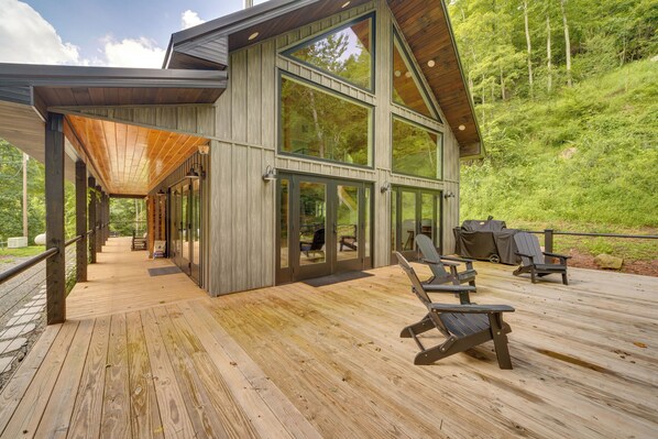 A modern wooden deck with outdoor seating and a glass-enclosed building.
