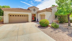 A two-story house with a garage, a covered entryway, and a landscaped front yard with a small tree and shrubs. - Pool, Hot Tub, Toys! Family Home, 4 Mi to Luke AFB (Litchfield Park)