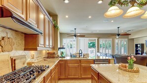 A kitchen with wooden cabinets, granite countertops, a gas stove, and pendant lighting. - Pool, Hot Tub, Toys! Family Home, 4 Mi to Luke AFB (Litchfield Park)