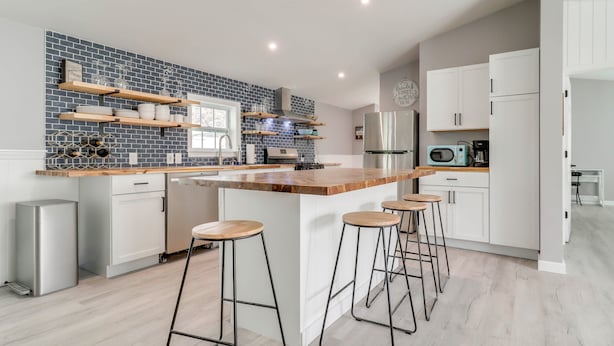 A modern kitchen with a central island, bar stools, and built-in shelves. - Walk to Yacht Club! Devils Lake Escape (Manitou Beach)