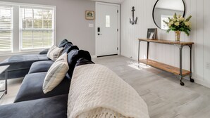 A modern living room with a sectional sofa, a console table with a mirror, and a door with a small window. - Walk to Yacht Club! Devils Lake Escape (Manitou Beach)