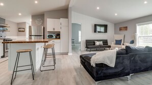 A modern kitchen with a central island, white cabinetry, and a ceiling fan. - Walk to Yacht Club! Devils Lake Escape (Manitou Beach)