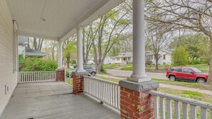 A covered porch with a white railing, brick columns, and a view of a residential street. - < 1 Mi to Uiuc! Family Game Day Hub w/ Large Yard (Champaign)