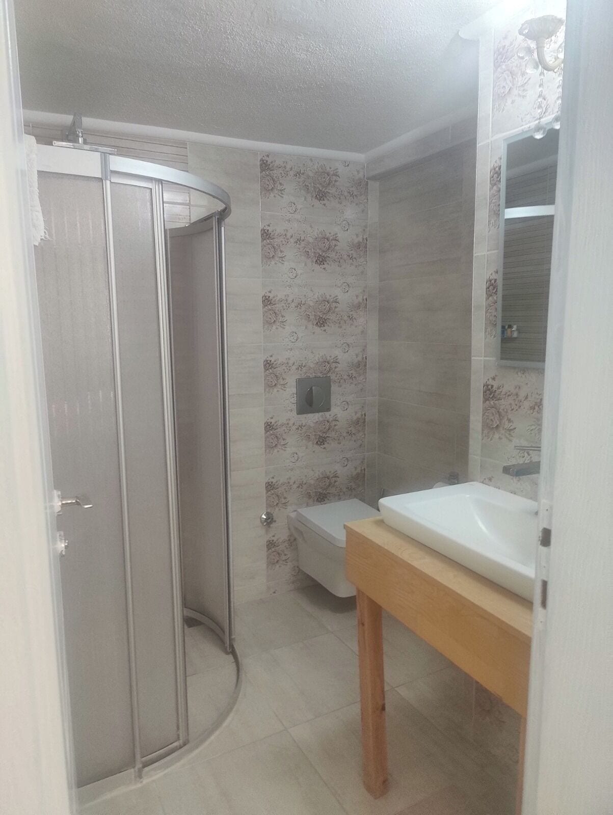A bathroom with a shower enclosure, toilet, and sink.