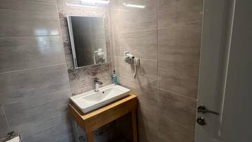A bathroom with a sink, mirror, toilet, and a door.