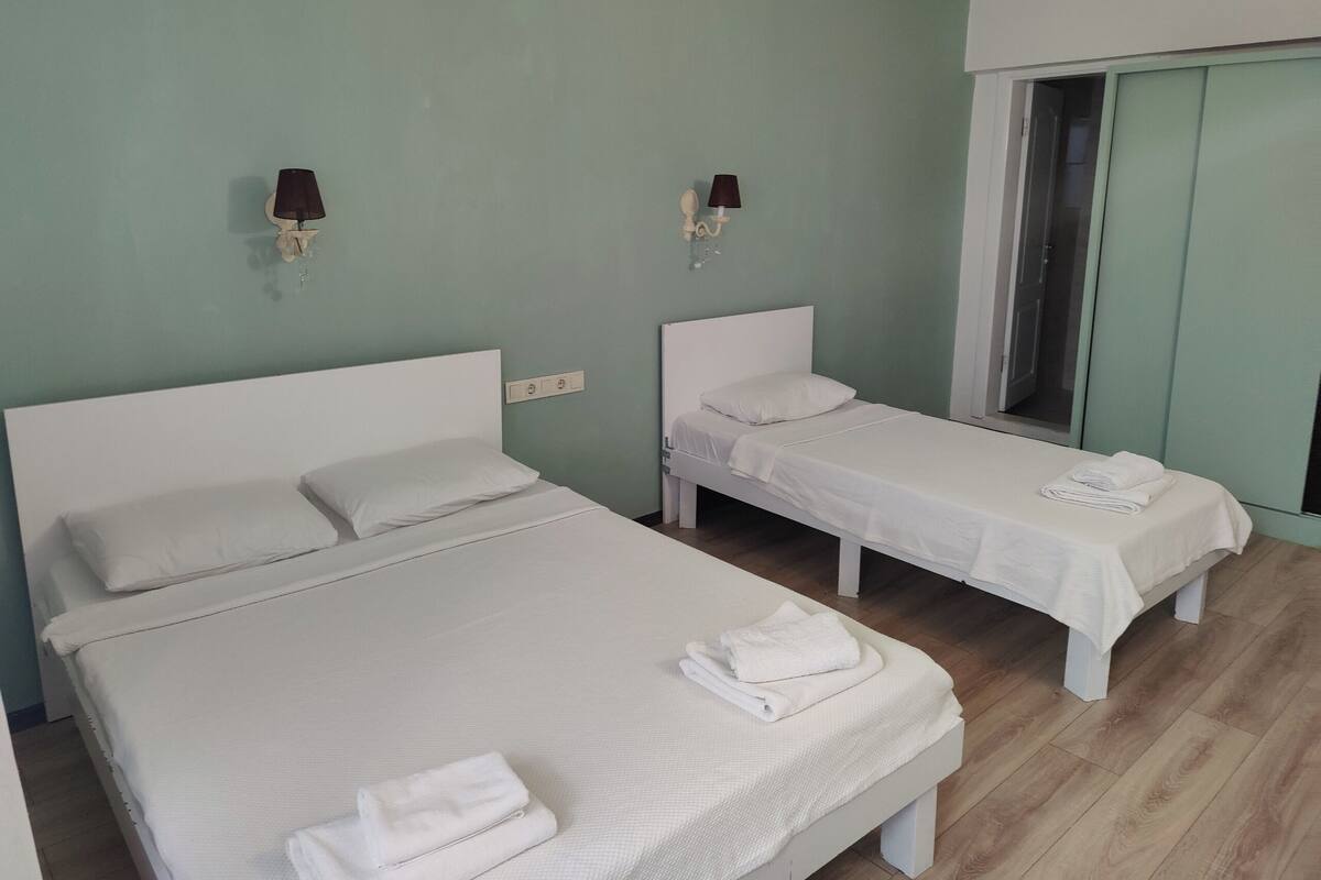 A room with two beds, a wardrobe, and a mirror.