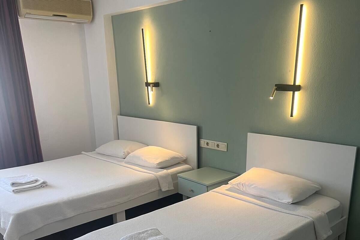 A hotel room with two single beds, each with a white headboard and a bedside table.