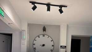 A reception desk with a clock above it, a sign with a phone number, and a door to the left.