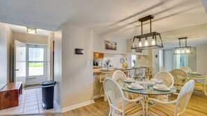 A dining area with wicker chairs, a glass table, and a modern light fixture. - 2 Mi to Sand! Port Charlotte Condo w/ Pool Access (Punta Gorda)