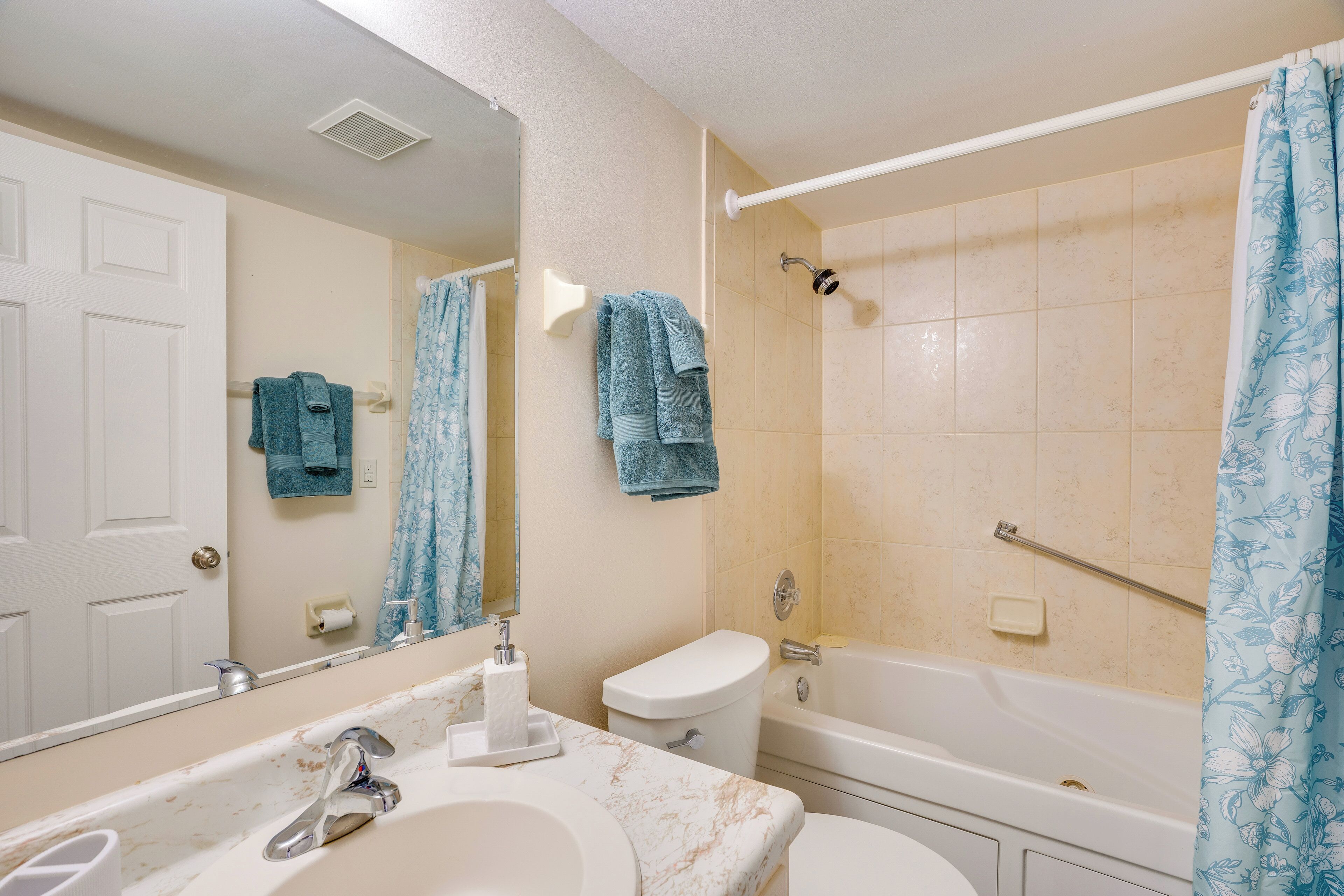 A bathroom with a sink, mirror, toilet, and bathtub.