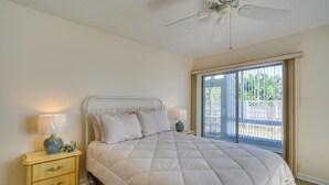 A bedroom with a bed, a nightstand, a lamp, a ceiling fan, and a view of the outdoors. - 2 Mi to Sand! Port Charlotte Condo w/ Pool Access (Punta Gorda)