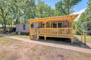 A wooden decked structure with a porch, a small staircase, and a window. - Lake Tawakoni Basecamp: Covered Patio + Fire Pit! (Wills Point)