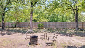 An outdoor area with a dirt ground, a metal fire pit, and metal chairs. - Lake Tawakoni Basecamp: Covered Patio + Fire Pit! (Wills Point)