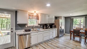 A modern kitchen with white cabinets, a dishwasher, a microwave, and a refrigerator. - Lake Tawakoni Basecamp: Covered Patio + Fire Pit! (Wills Point)