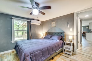 A bedroom with a bed, a ceiling fan, a window, and a nightstand. - Lake Tawakoni Basecamp: Covered Patio + Fire Pit! (Wills Point)