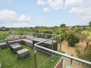 Een dakterras met een modulaire bank, tuinmeubilair en uitzicht op een wijngaard.