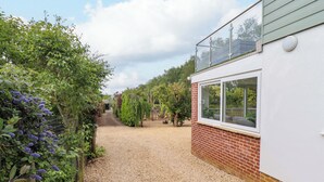 Ein Kiesweg führt zu einem Haus mit Ziegelaußenwänden und einem weißen Fenster.