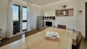 Eine moderne Küche mit Essbereich, einem Kühlschrank, einem Fernseher und einem kleinen Regal mit Dekoration.
