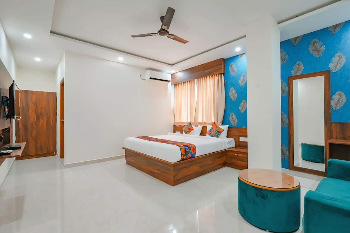 A modern hotel room with a bed, a ceiling fan, a TV, and a bathroom.