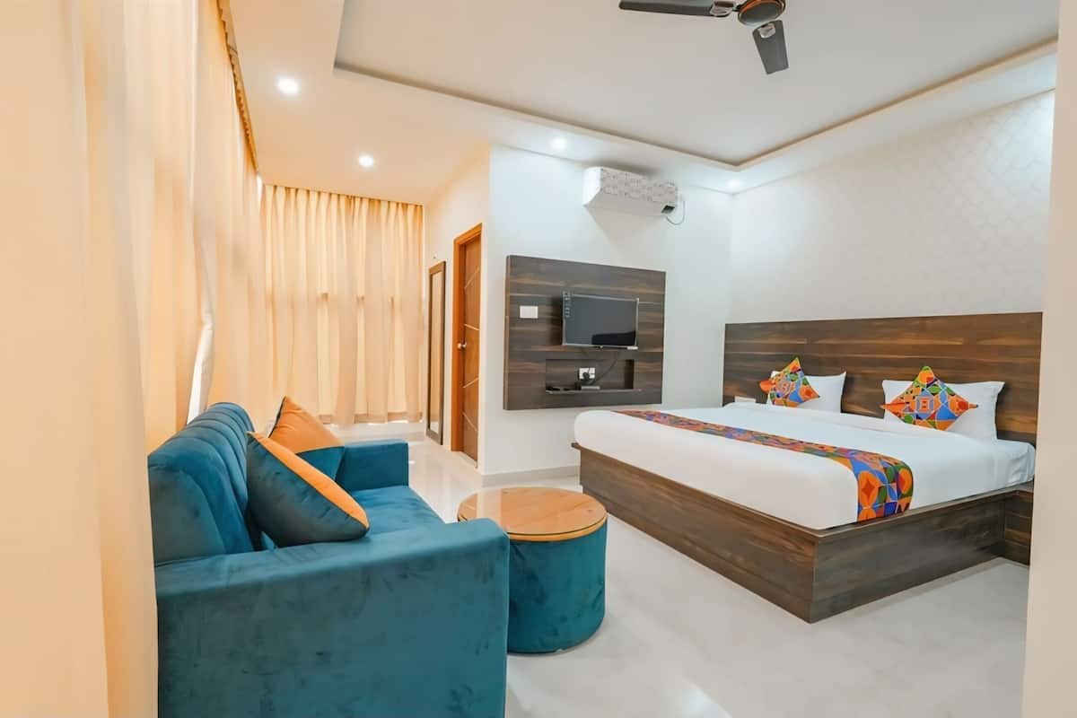 A modern hotel room with a large bed, a sofa, a TV, and a ceiling fan.