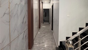 Un pasillo con paredes de mármol y una escalera con barandilla de metal.