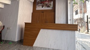Un área de recepción con un mostrador de madera, piso de mármol e iluminación empotrada en el techo.