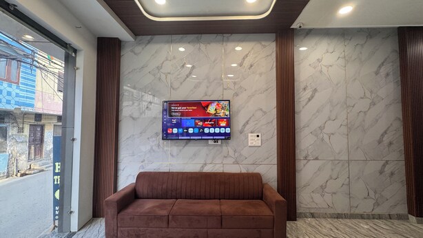 Un vestíbulo moderno con una pared de mármol, un televisor montado y un sofá marrón.