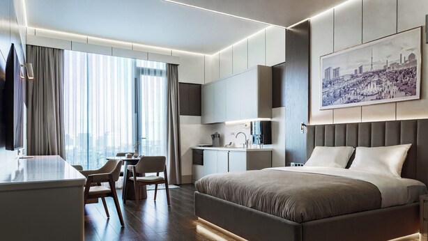Una habitación de hotel moderna con una cama grande, un escritorio y vistas a la ciudad.