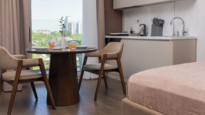Una habitación de hotel moderna con comedor, kitchenette y vistas a la ciudad.