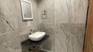 A bathroom with a marble wall, a sink, and a framed picture. - Hotel H - 22 (Noida)
