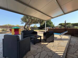 Ein Patio im Freien mit Korbmöbeln, einem Pool und einem überdachten Bereich.