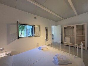 Ein Schlafzimmer mit Bett, Fenster, Kleiderschrank und Spiegel.