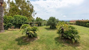A well-maintained garden with a pergola, various shrubs, and a view of a distant building. - Room 'Camera Rosa' with Mountain View, Wi-Fi and Air Conditioning (Pontecagnano Faiano)