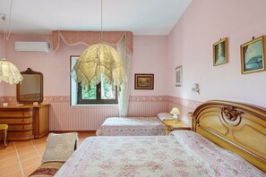 A bedroom with two beds, a dresser, a mirror, and a window with a view.
