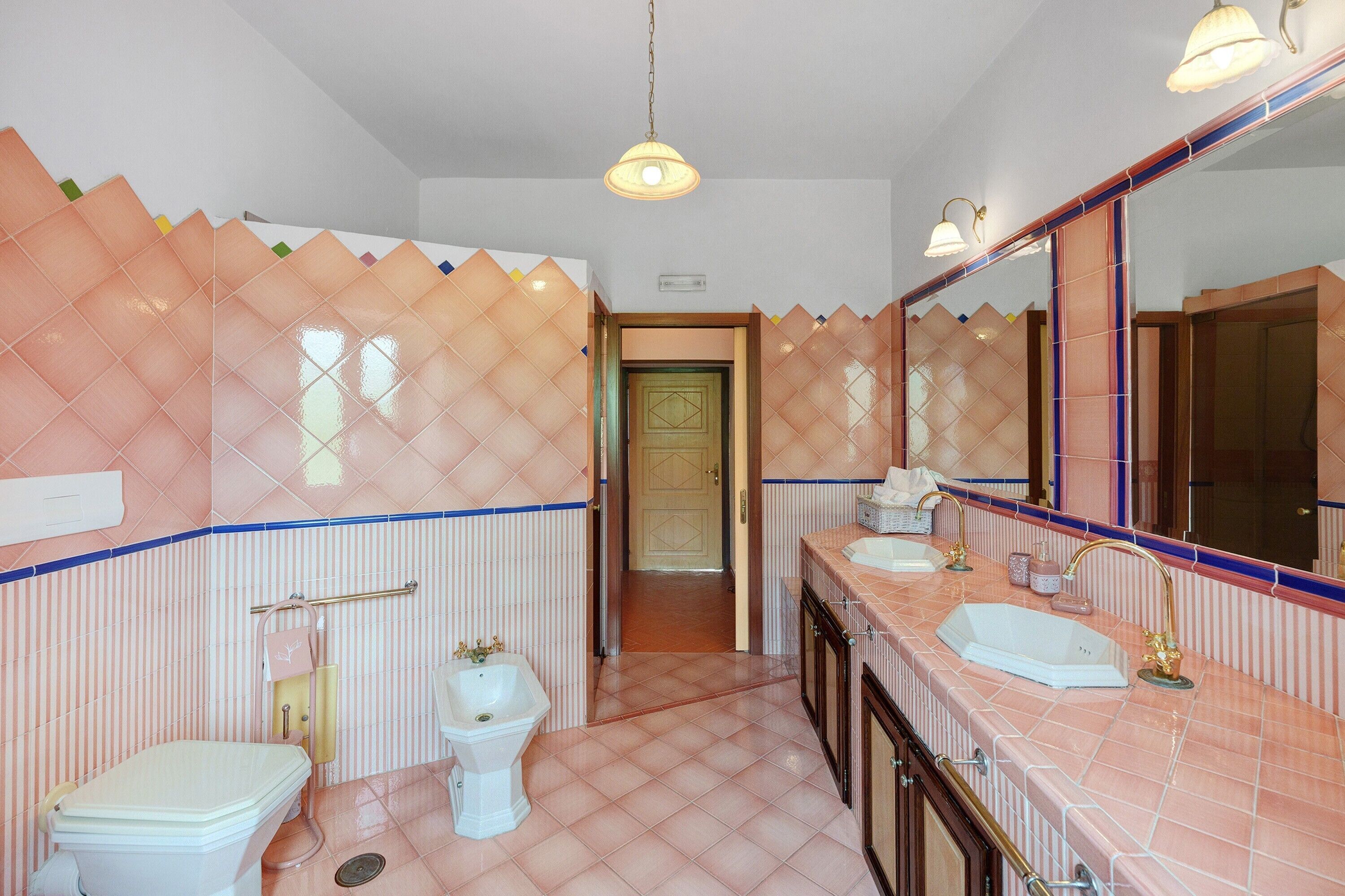 A bathroom with a toilet, bidet, sink, and mirror.