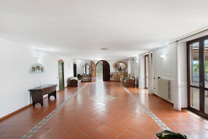 A spacious hallway with a tiled floor, a bench, and a radiator.