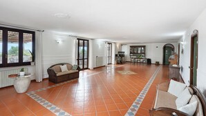 A spacious living area with a sofa, a coffee table, and a dining table. - Room 'Camera Rosa' with Mountain View, Wi-Fi and Air Conditioning (Pontecagnano Faiano)