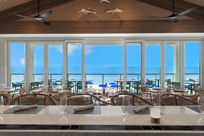 A restaurant with a view of the ocean, large windows, and ceiling fans. - West Bay Club first floor Coach Home with Lake View (Estero)