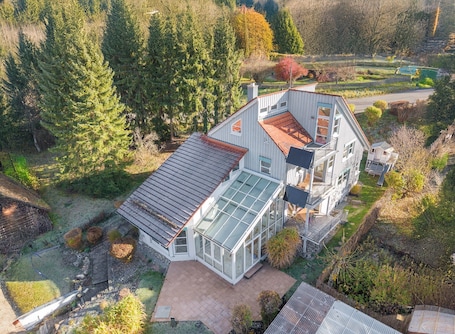 A house with a large glass conservatory, a sloped roof, and a fenced yard.
